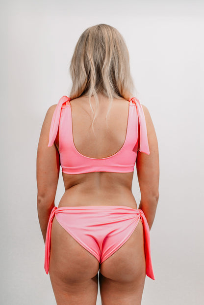 Charlotte wears the Marisol Bikini Top in size XS. Back view.