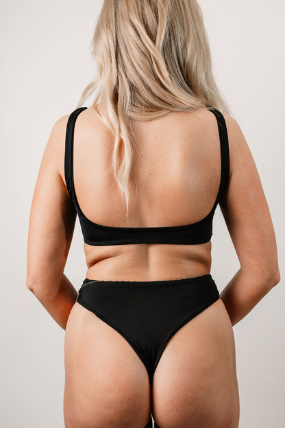 Charlotte wears the Sabrina Thong Bottoms in size XS. Back view.