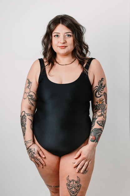 Cara wears the black Sailor One Piece in size M. Front view.
