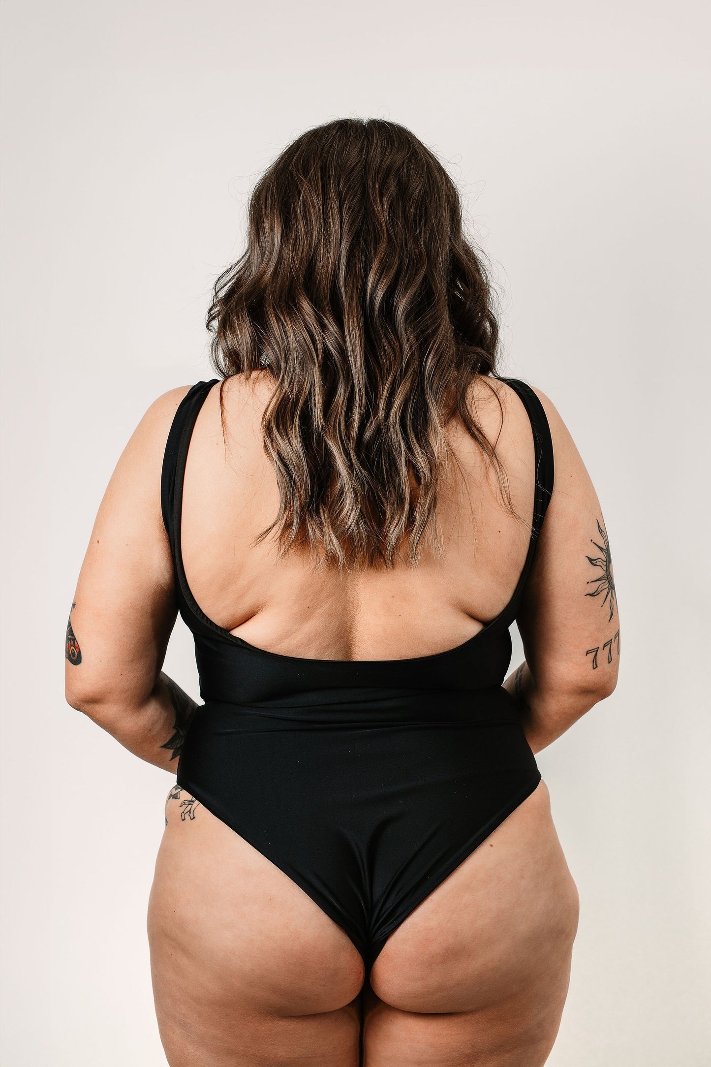 Cara wears the black Sailor One Piece in size M. Back view.