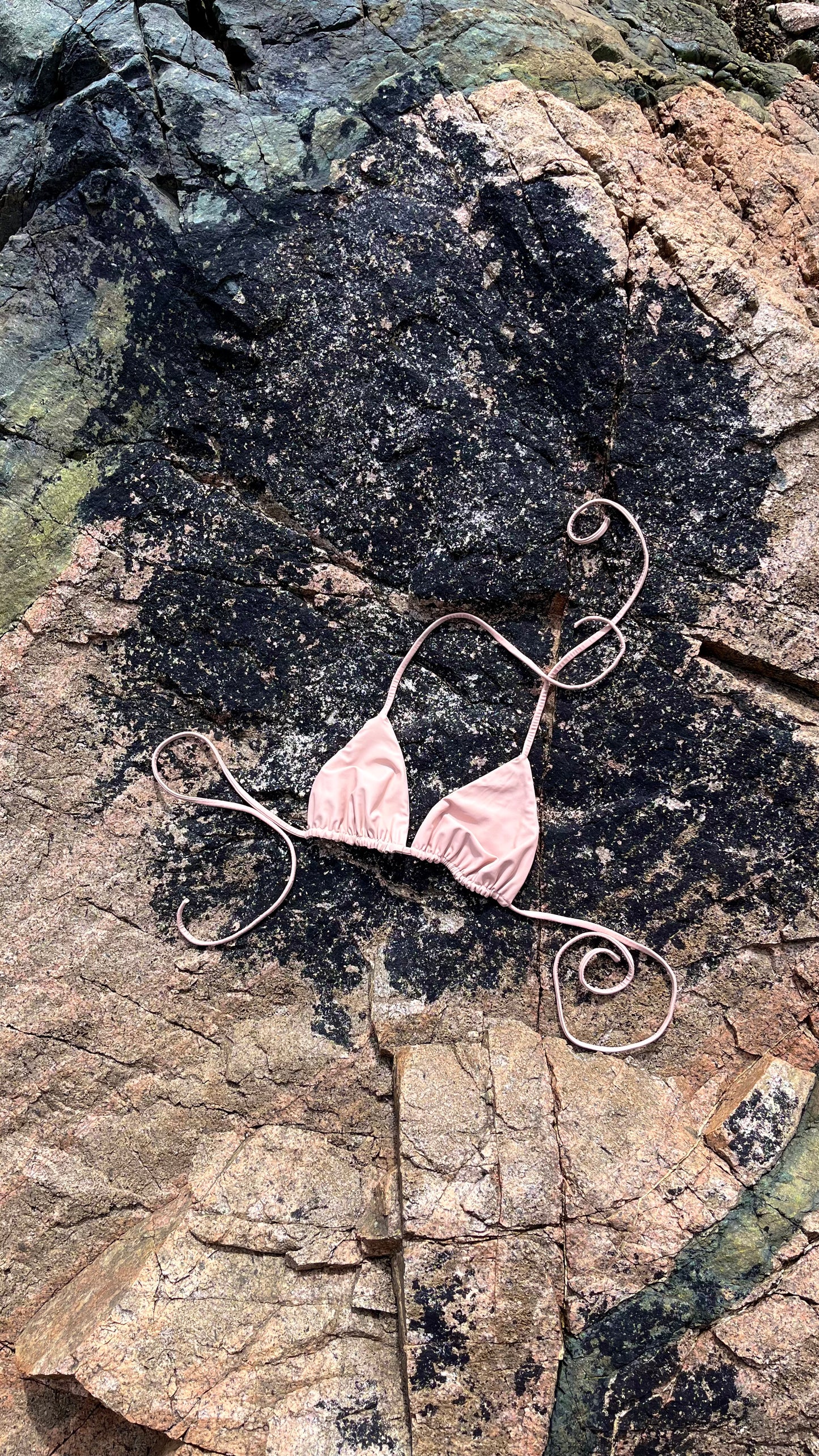 The Bella Bikini Top laid on the rock in Sand.